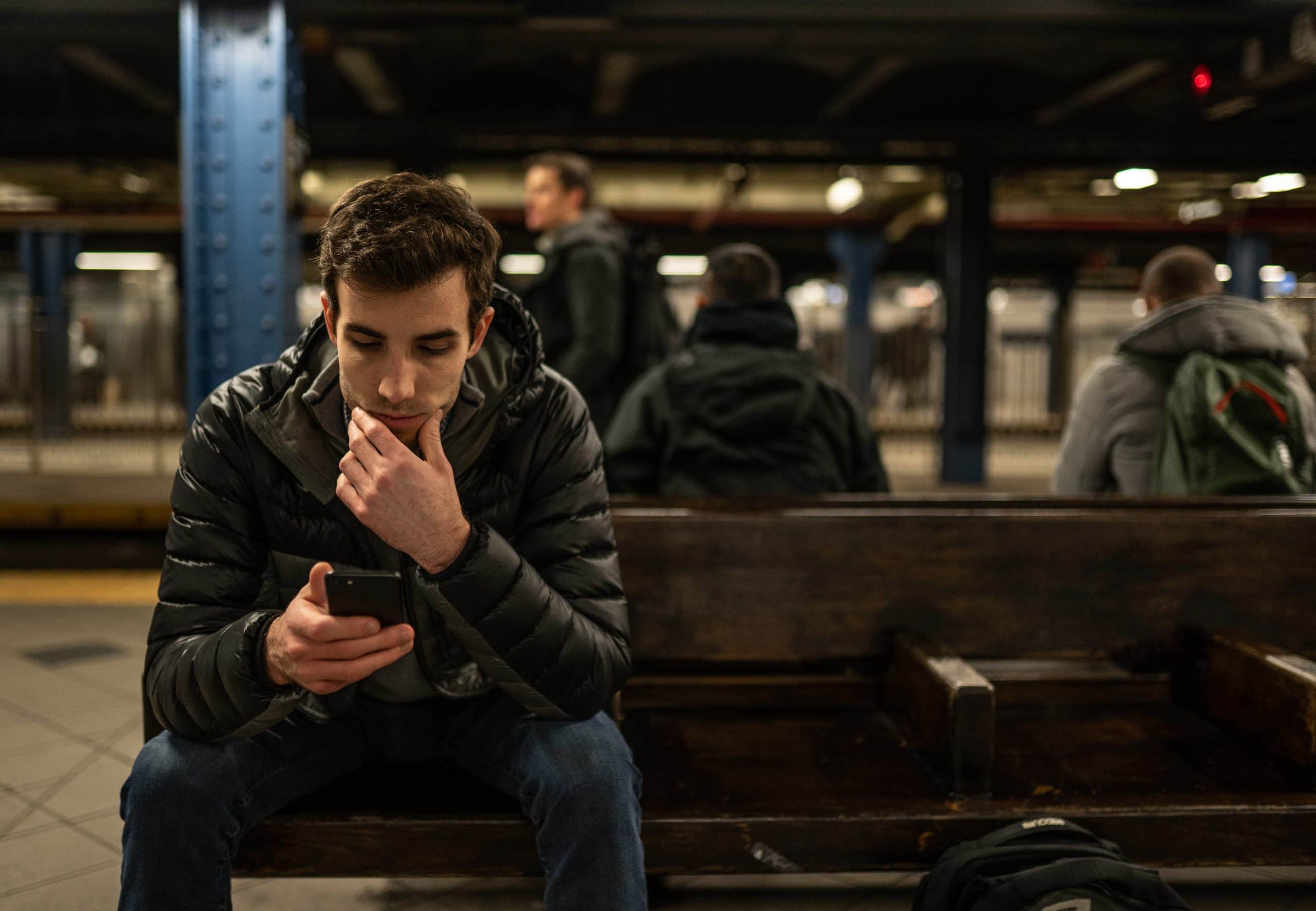 Man looking at his phone while sitting on a bench