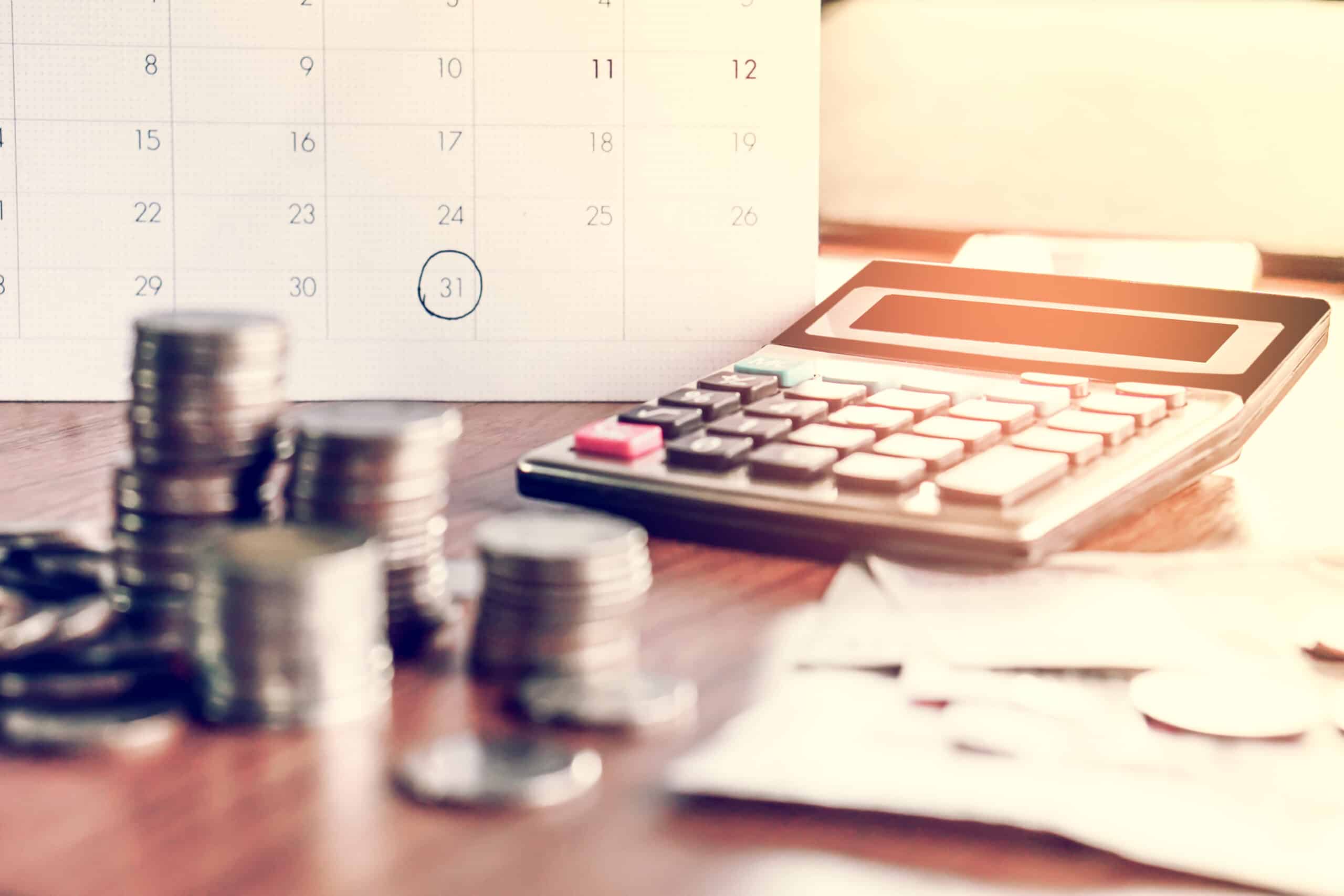 Money, a calculator, and a calendar showing bills due date.