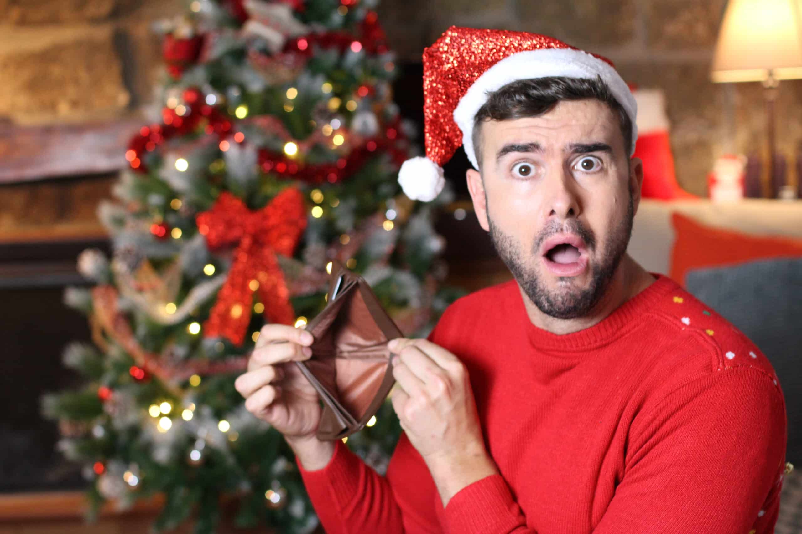 Man in front of holiday decorations showing an empty wallet
