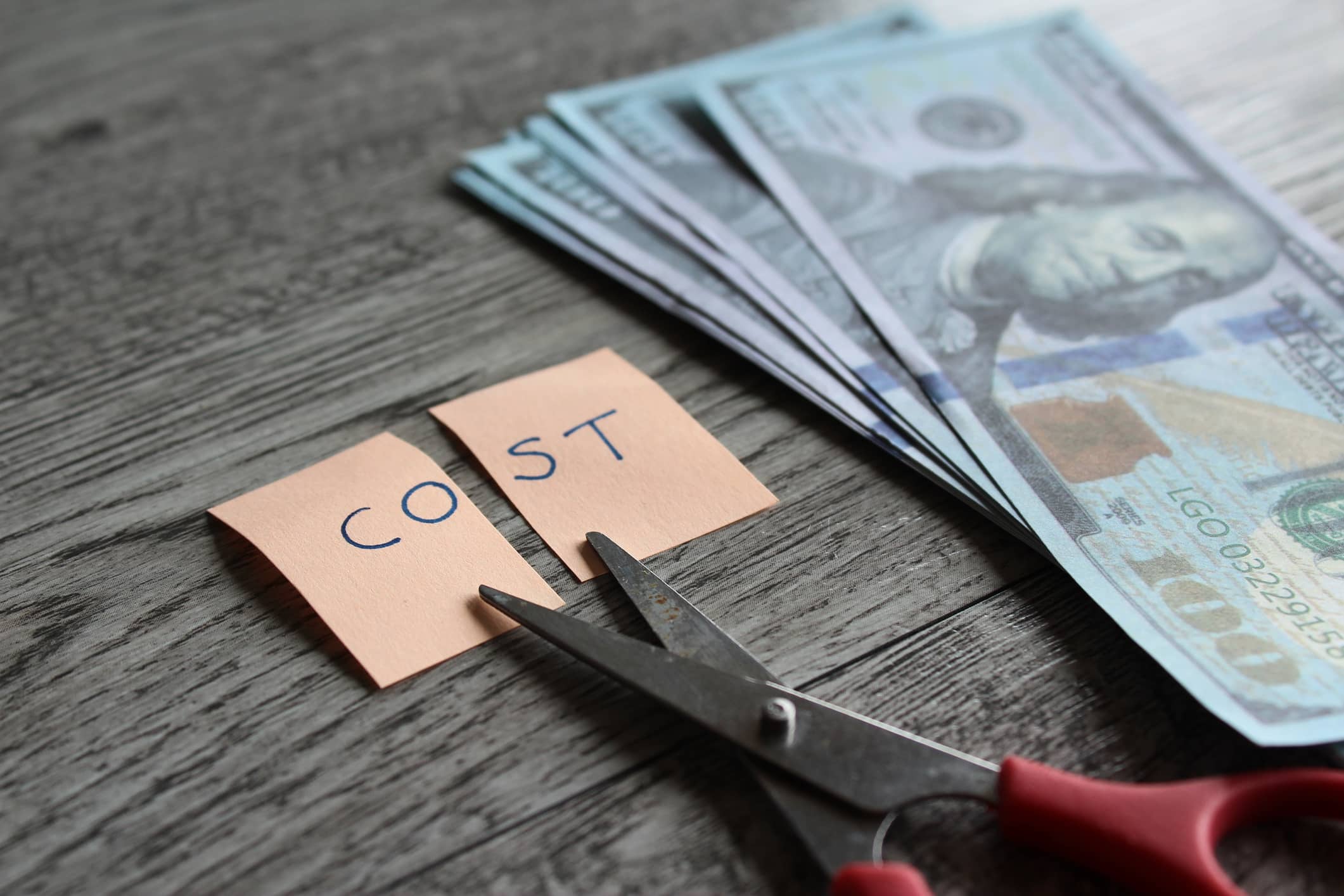 How to cut expenses. Scissor, money and note with text COST. Financial, cost cutting, reduce expenses concept