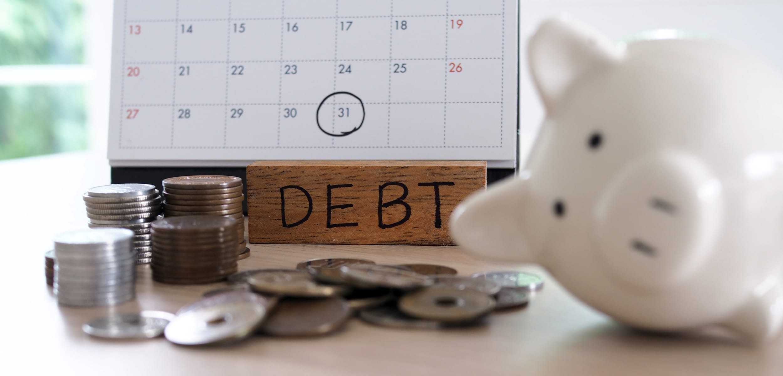 Pay off debt or save. Due for repayment There are coins, calculators and calendar reminders placed on the table.