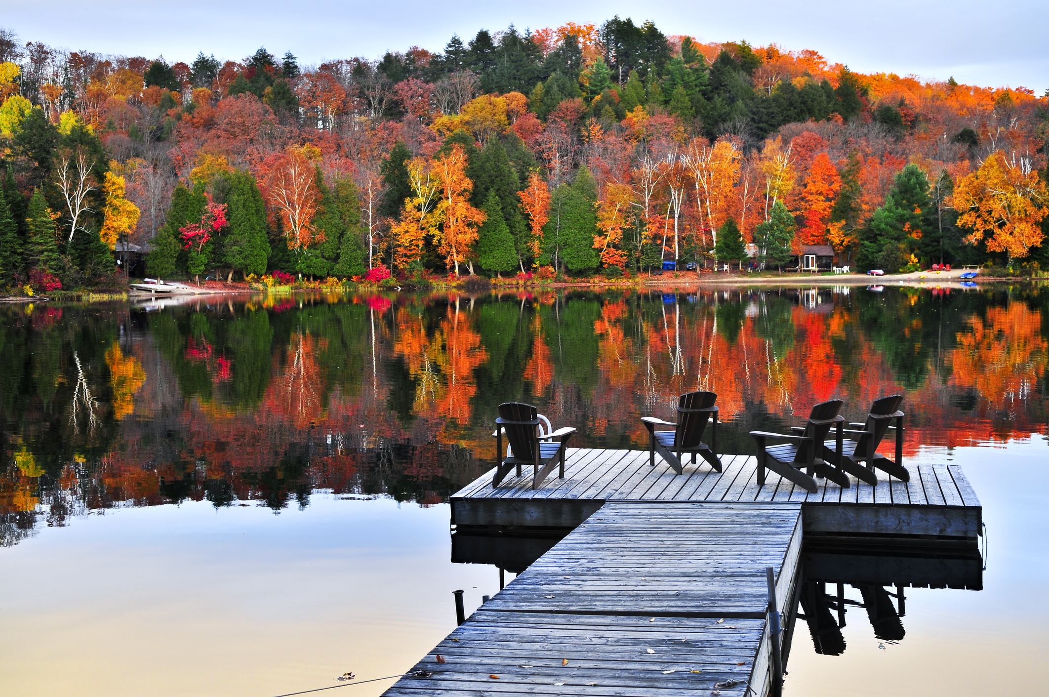 fall vacation ideas. Wooden dock with chairs on calm fall lake