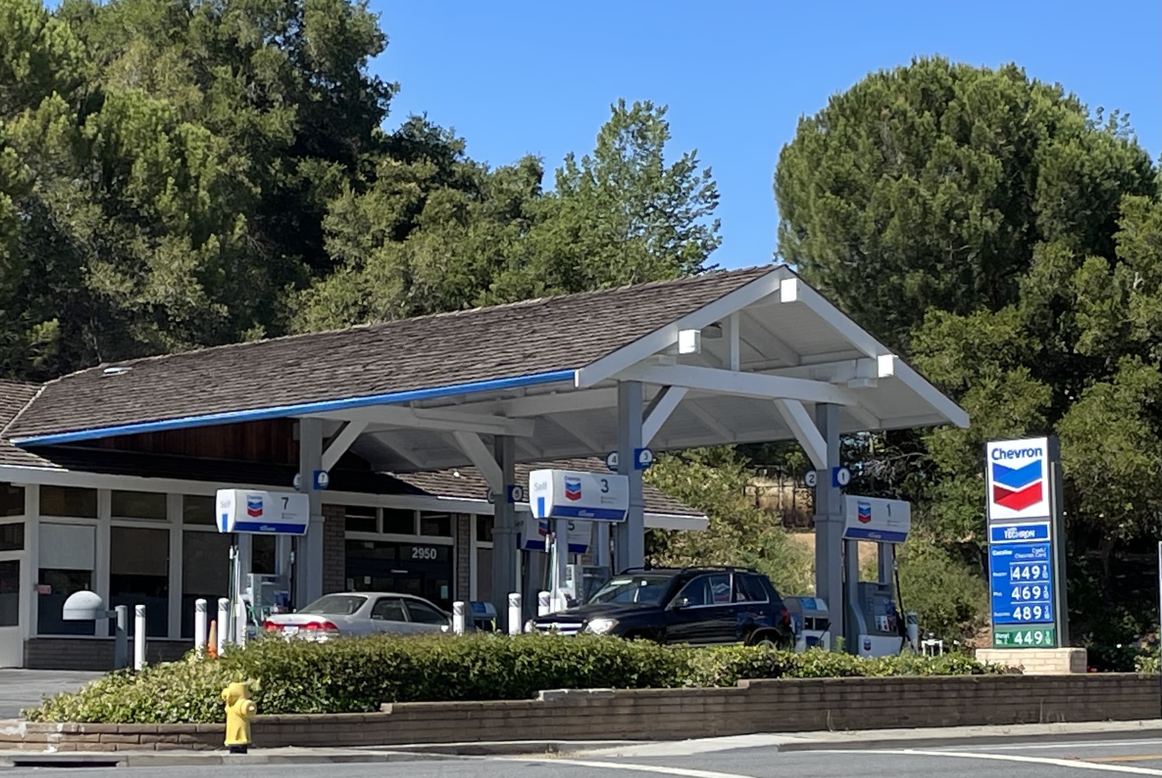 save on gas. picture of a gas station with trees and blue sky in background.