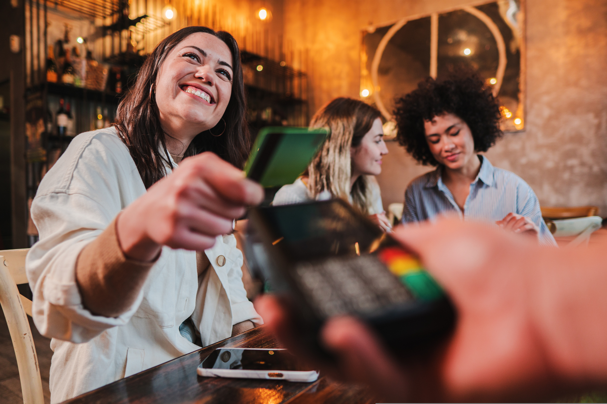 Smiling young woman holding credit card out to pay for something. how much does a credit card cost?