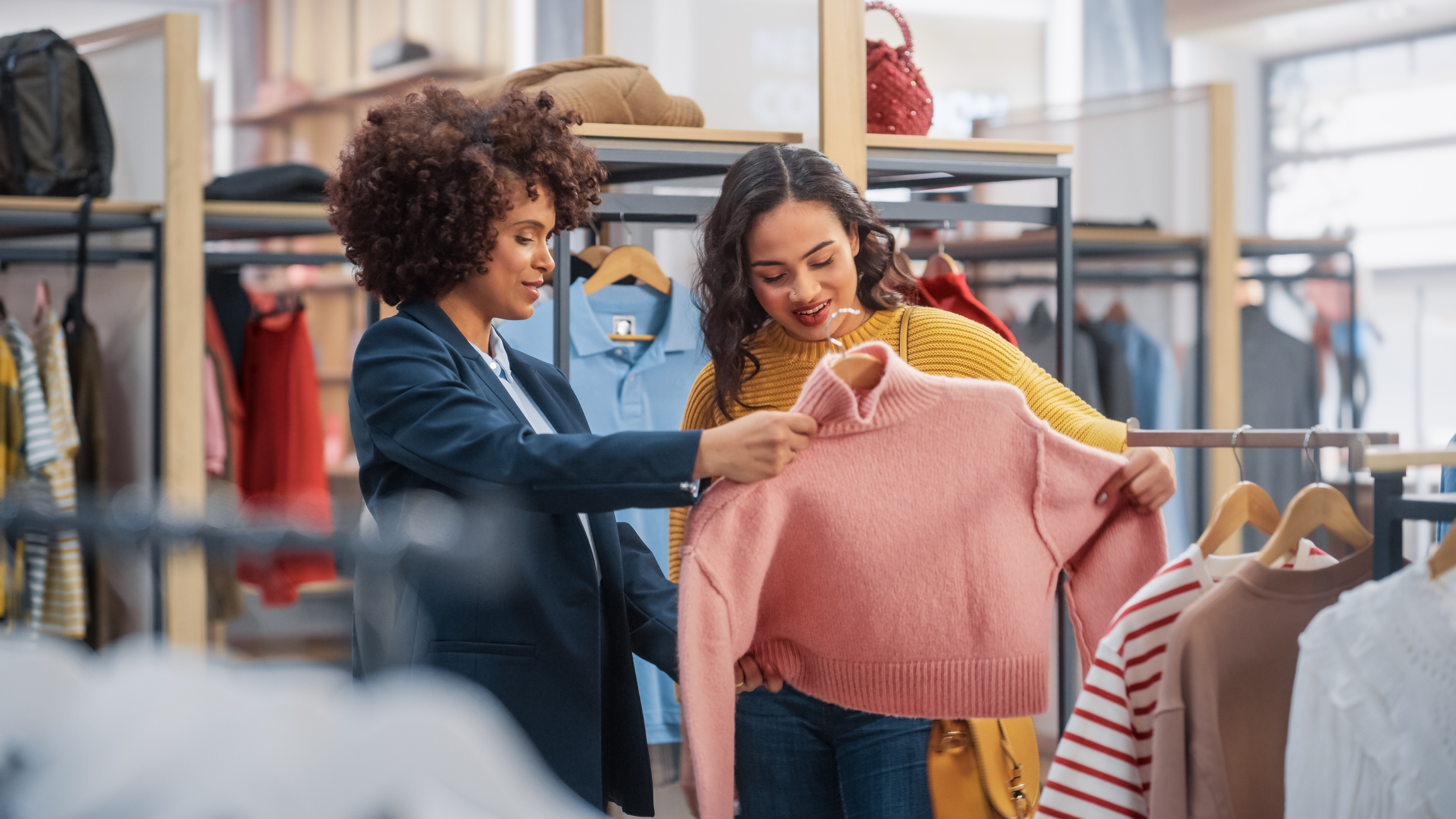 are outlet stores really a good deal? Two women looking at a sweater in a store.