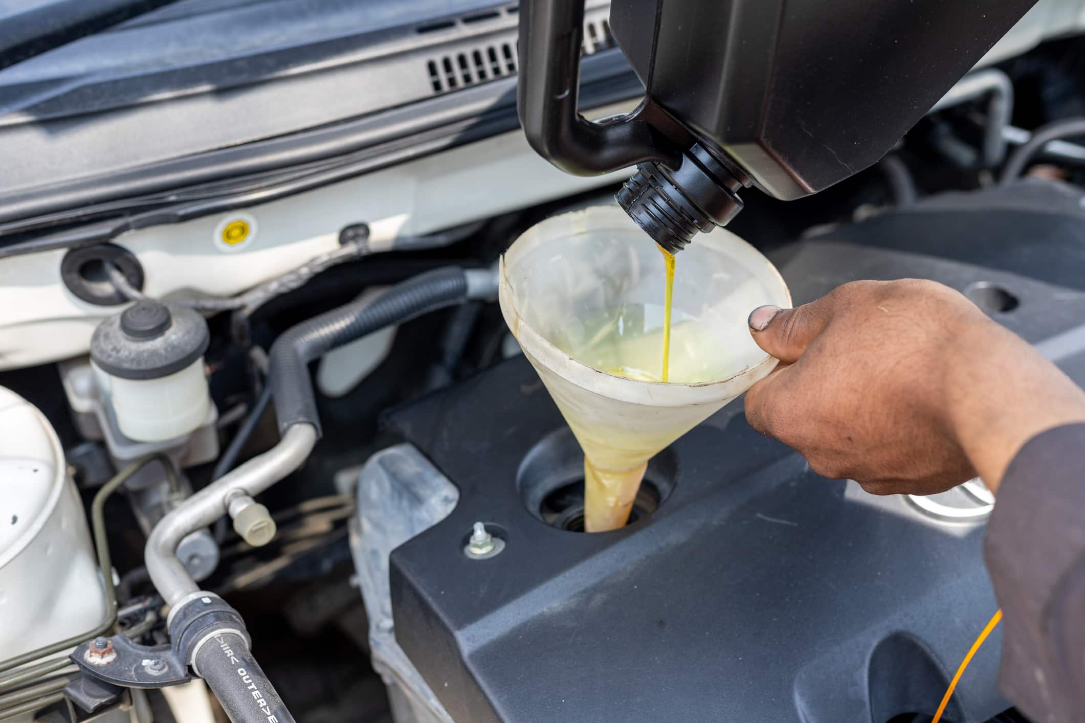 DIY oil change. Pouring motor oil to engine with the help of a funnel