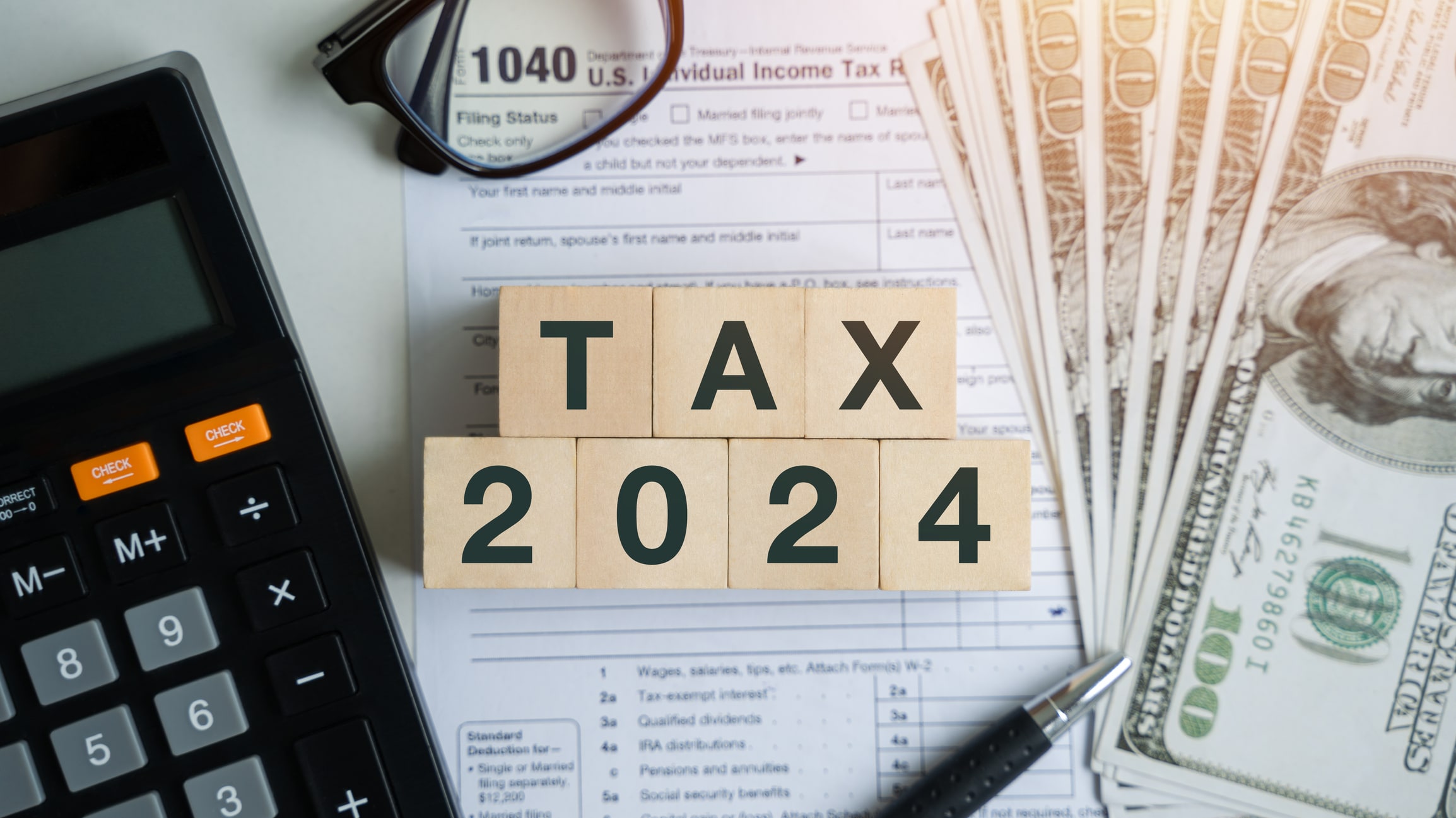 Tax credits 2024 on wooden blocks. Business and tax concept. Calculator, currency, book, tax forms. Financial calculations, tax, accounting, statistics and analytical research concepts.