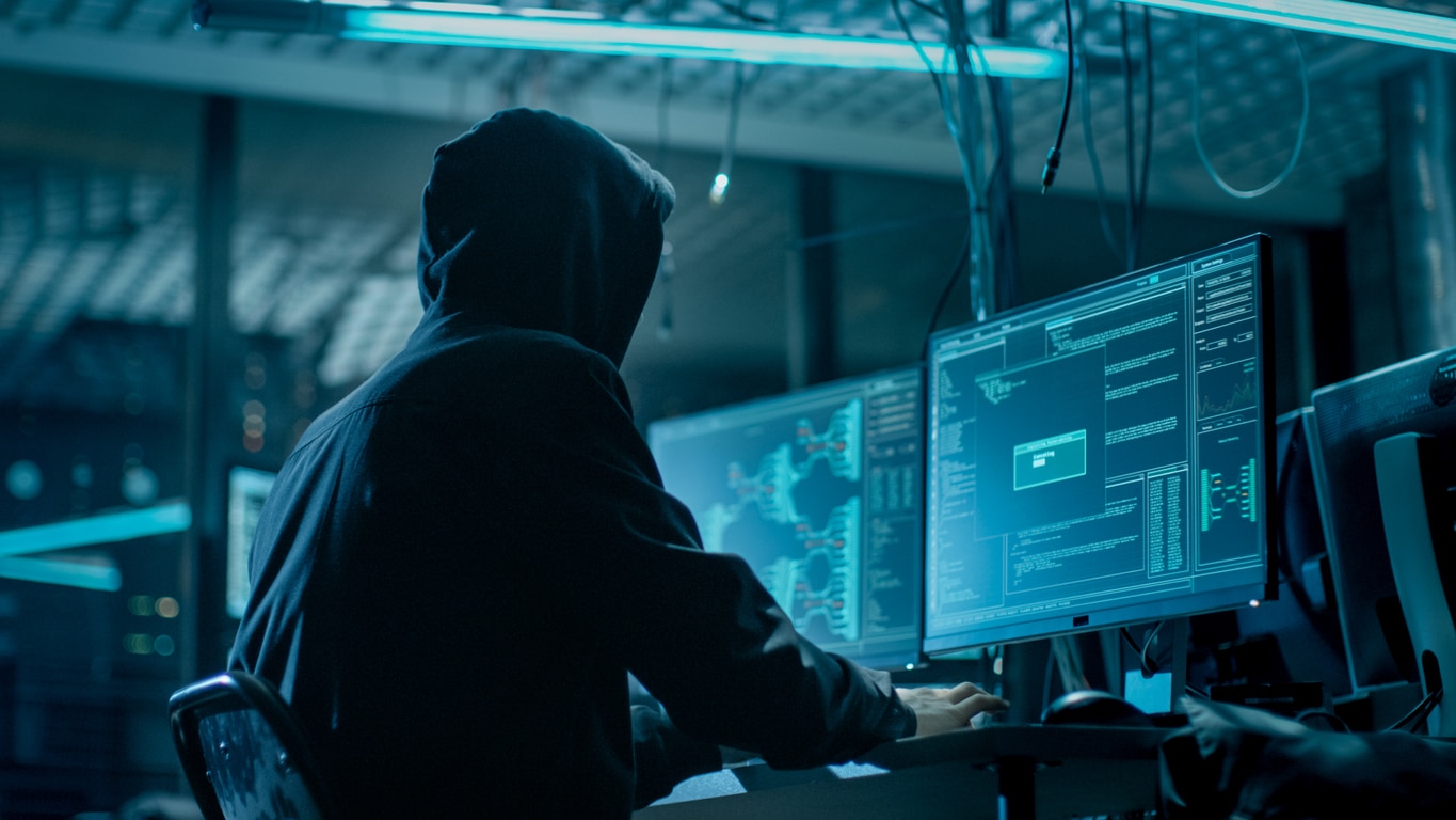 protect your accounts from hackers, figure at a computer in a black hoodie.